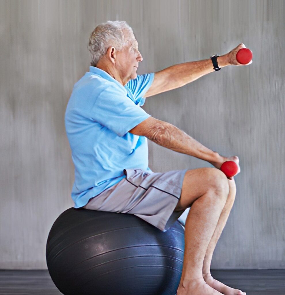 Senior man performing seated balance exercises with hand weights on a stability ball