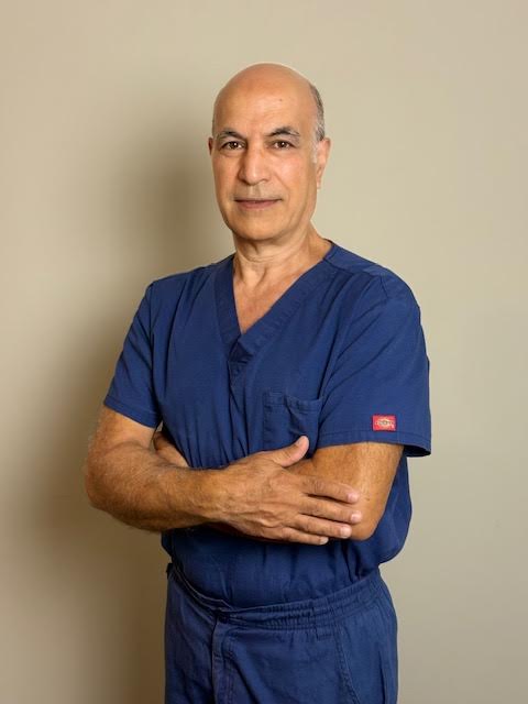 Amr, lead physical therapist at Motion Life Physical Therapy, wearing scrubs and standing with arms crossed