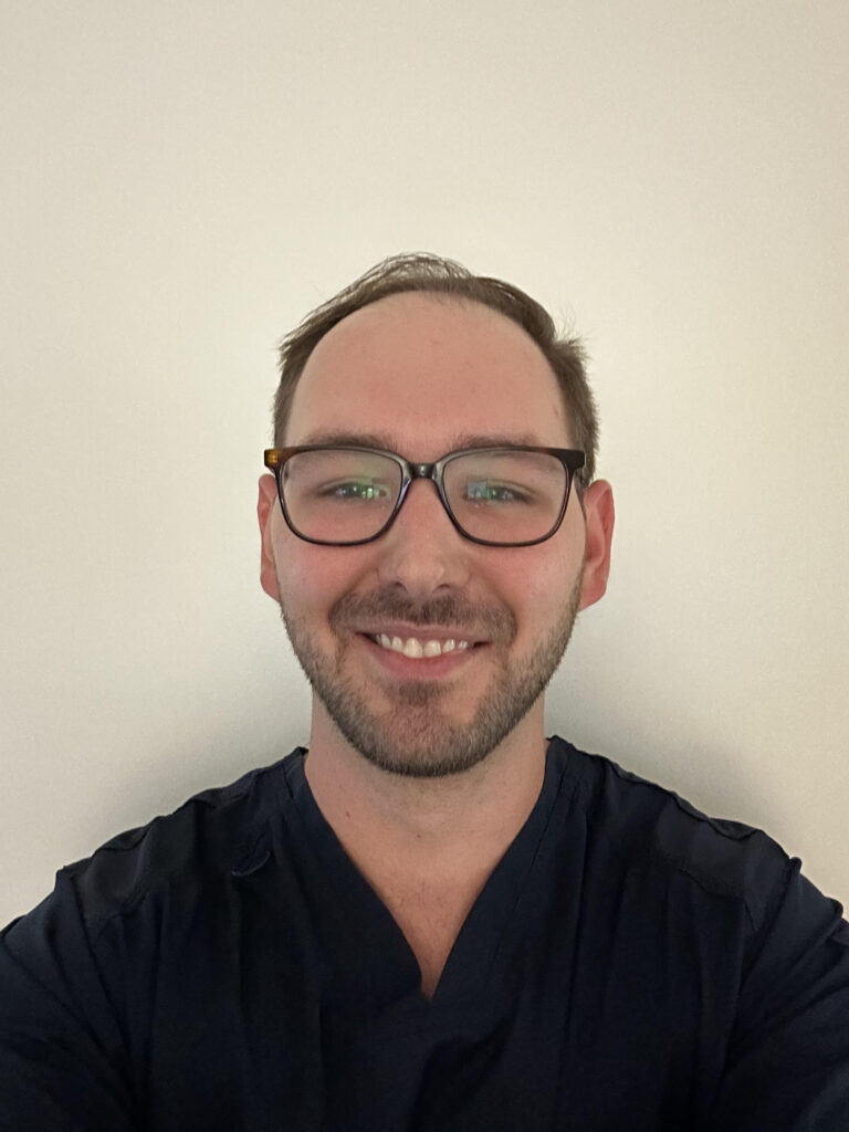 Jared Lyon, Physical Therapist Assistant at Motion Life Physical Therapy, smiling in navy scrubs
